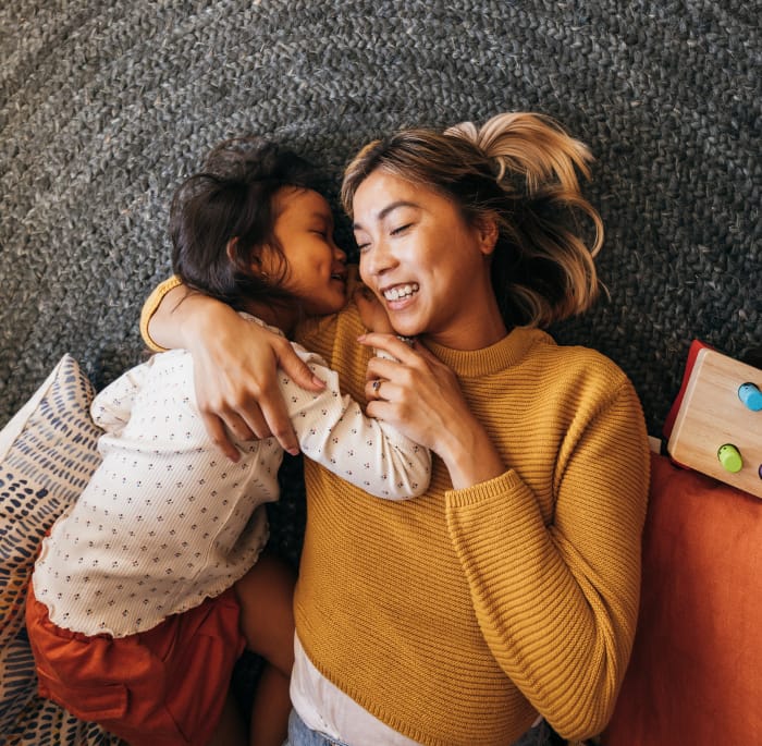 Mother and daughter laying down on a carpet