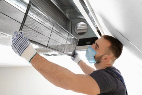 Air Duct Cleaning professional wearing a mask installing a new Air Duct in a home