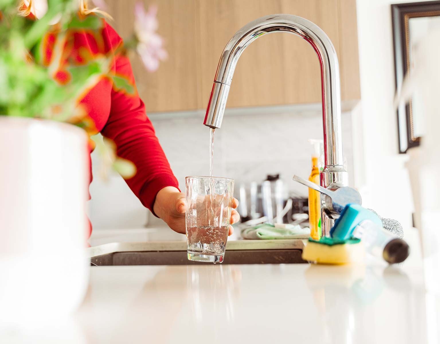 Someone filling a glass of water from the kitchen tap.