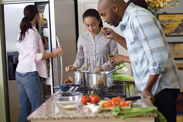 Family preparing meal around stove