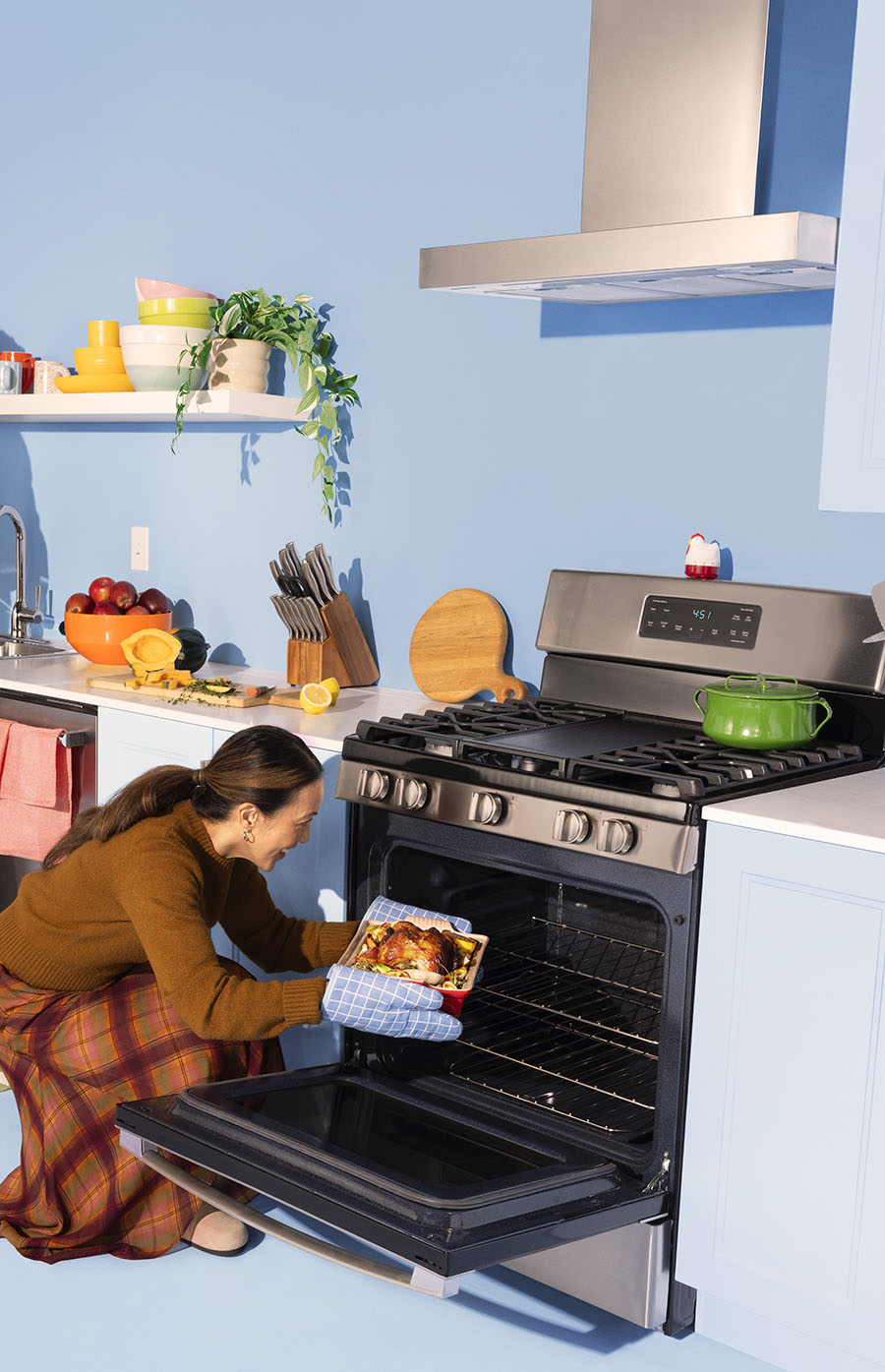 smiling woman pulling a roasted turkey out of the oven