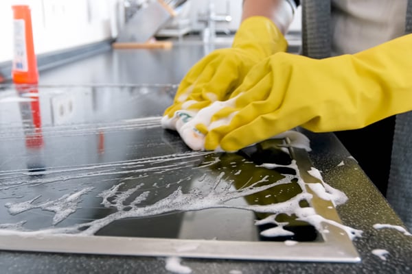 women cleaning a kitchen counter with a soapy sponge