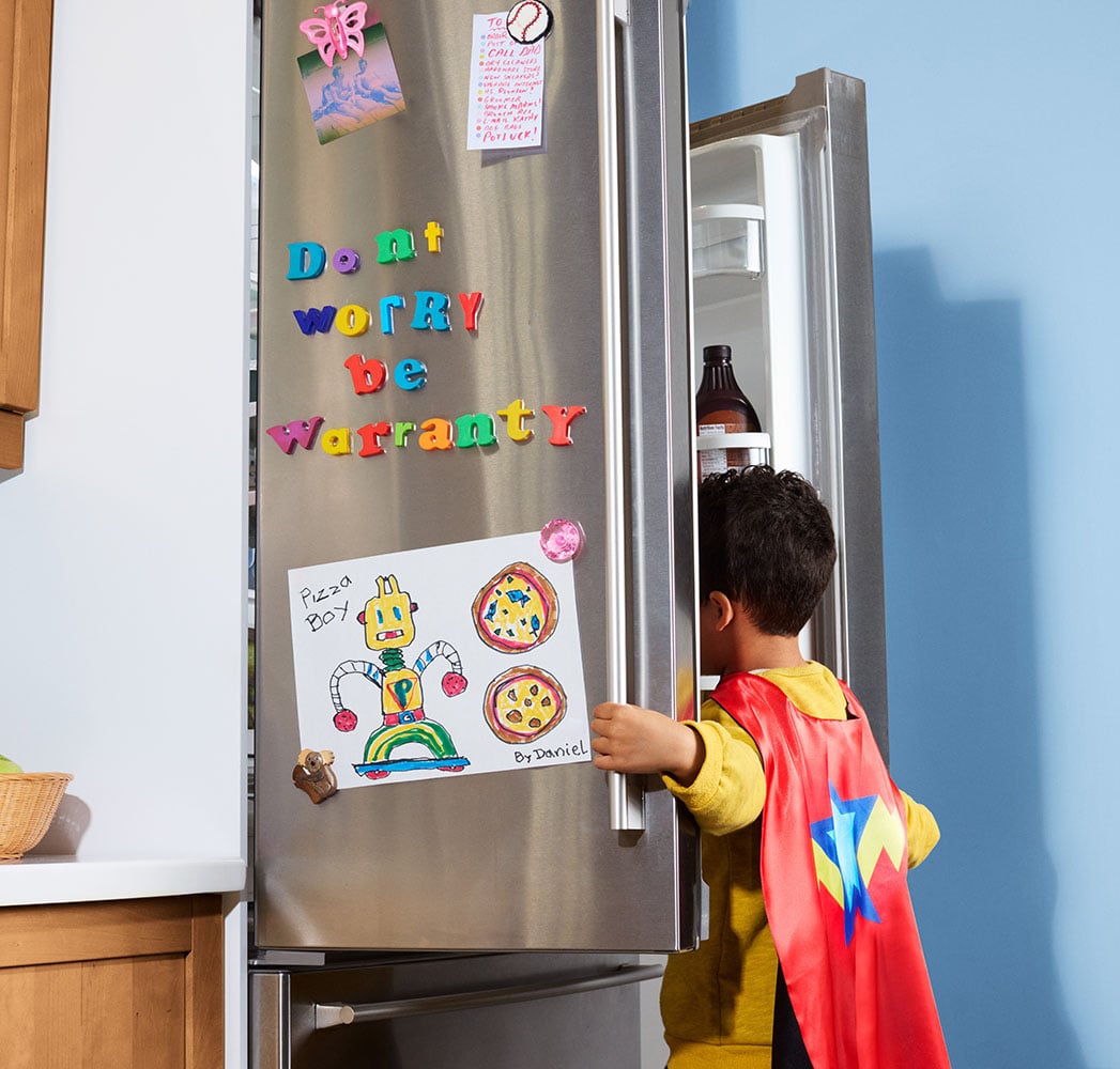 A child with a superhero cape on looking inside an open refrigerator.