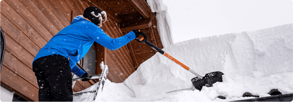 Person shoveling snow off roof