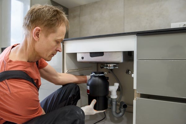 man installing garbage disposal