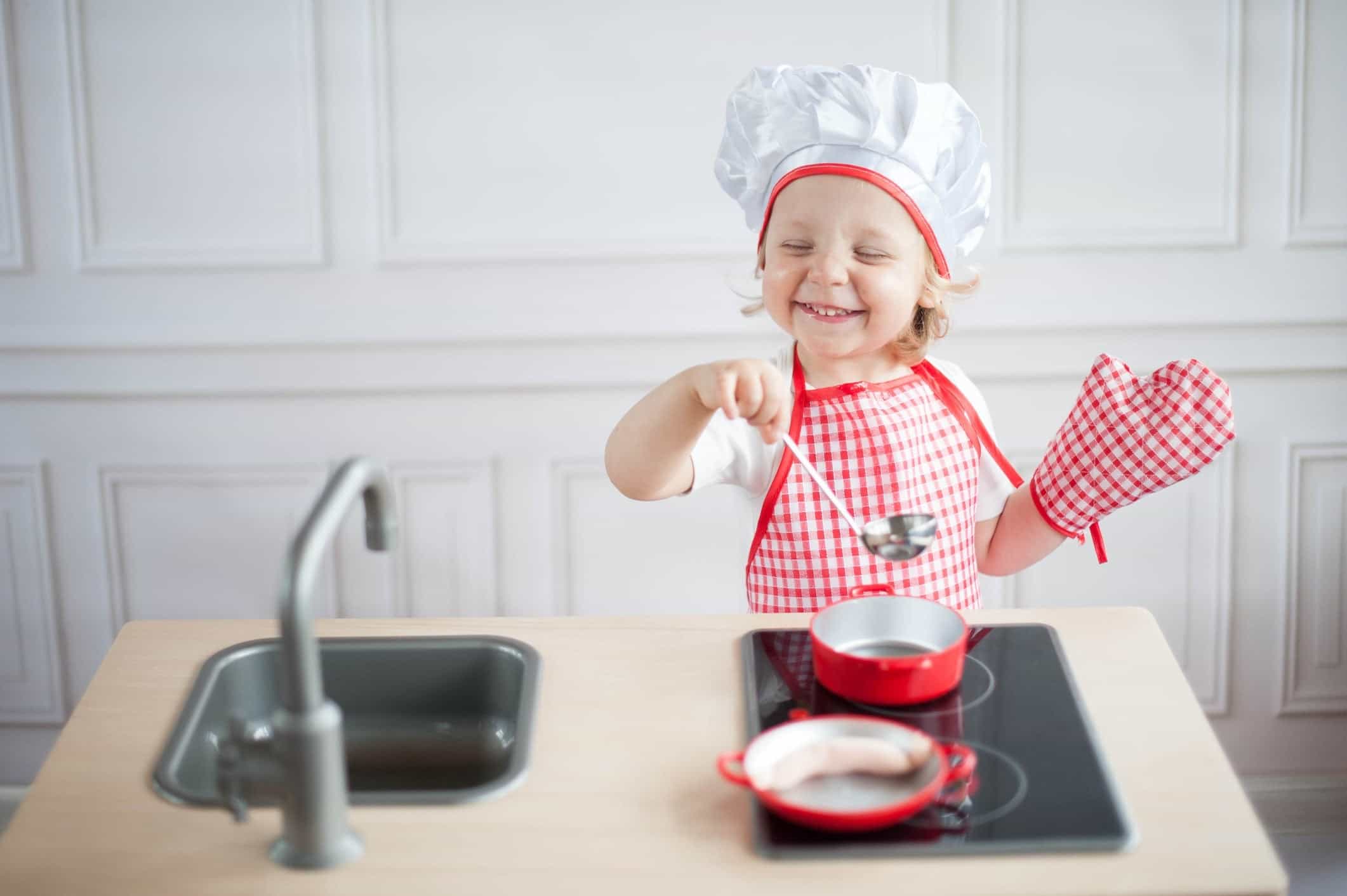 little girl wearing oven mitts