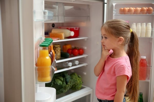 girl looking into open fridge