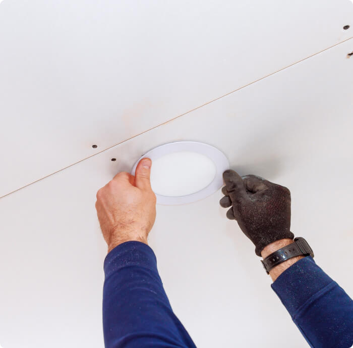 Two hands closeup installing a light fixture. One hand is gloved.